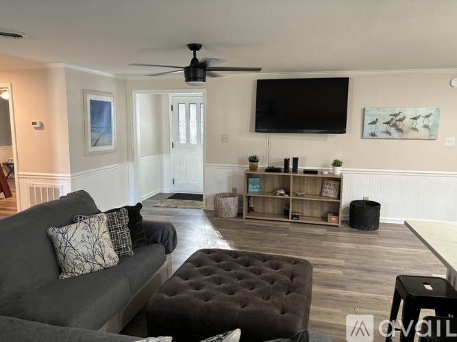 A living room with a grey couch and a black tufted ottoman.