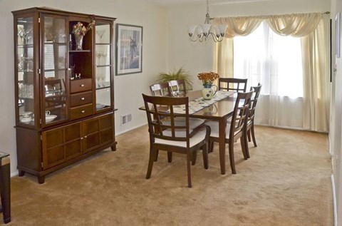 A dining room with a wooden table and chairs.