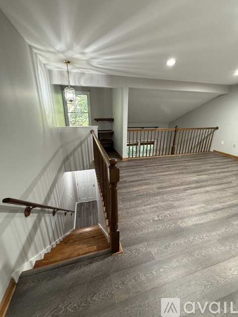 A spacious attic room with a staircase leading to the upper floor.