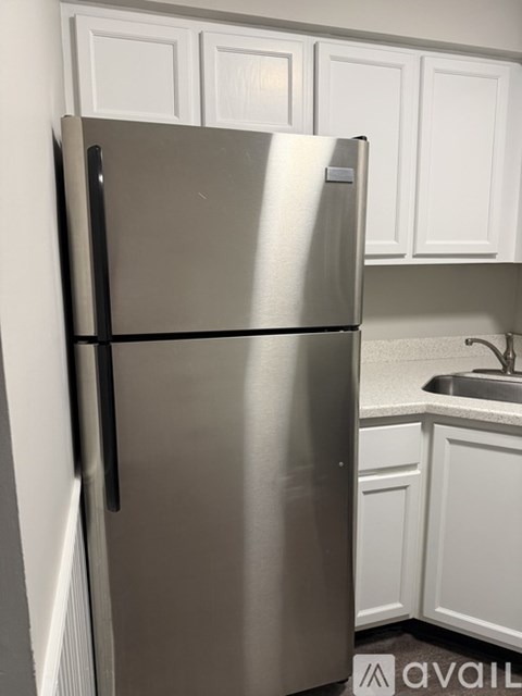 A stainless steel refrigerator in a kitchen with white cabinets.