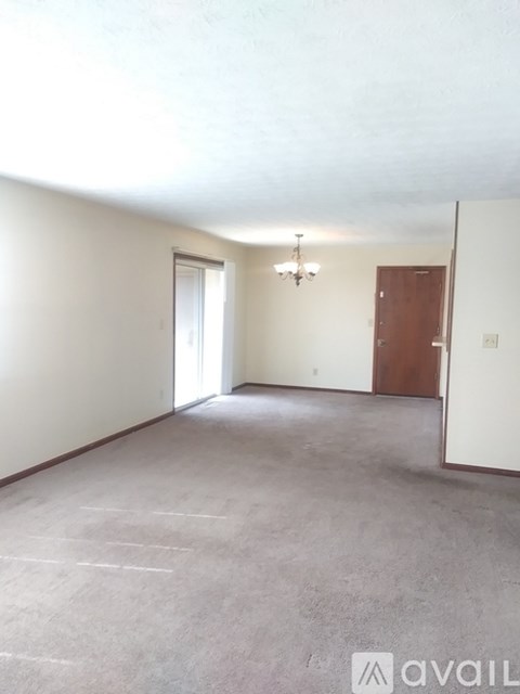 A room with a carpeted floor and a chandelier hanging from the ceiling.
