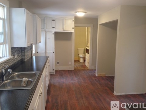 A kitchen with white cabinets and a black counter top.
