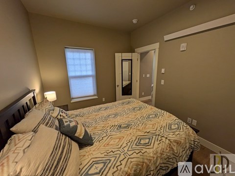 A bedroom with a bed, a window, and a door.