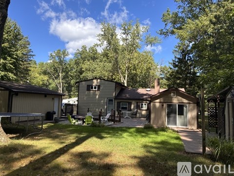 A house with a backyard and trees in the background.