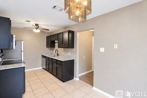 A kitchen with black cabinets and a fan on the ceiling.