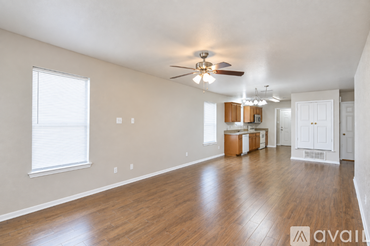 A spacious room with wooden floors and a ceiling fan.
