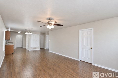 A spacious room with wooden floors and a ceiling fan.