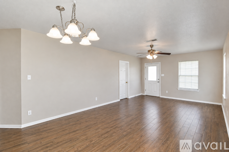 A spacious room with wooden floors and a ceiling fan.