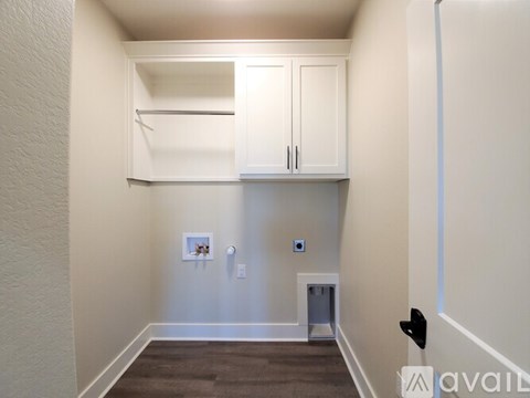 A small, empty room with a cabinet and a trash can.