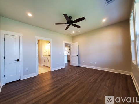 A spacious room with a ceiling fan and hardwood floors.