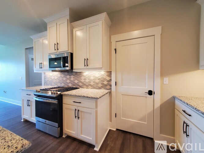 A kitchen with white cabinets and a black and white checkered backsplash.