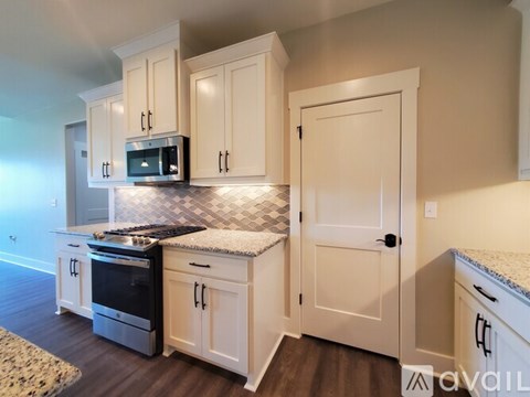 A kitchen with white cabinets and a black and white checkered backsplash.