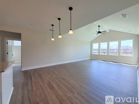 A spacious room with wooden flooring and a ceiling fan.