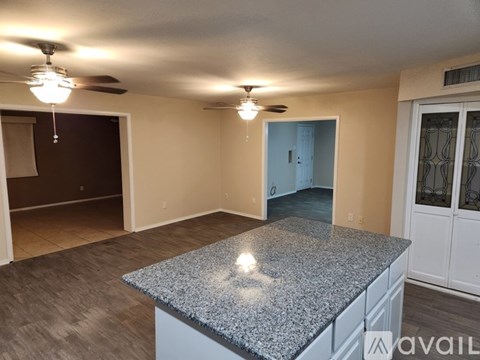A spacious room with a granite countertop and a ceiling fan.