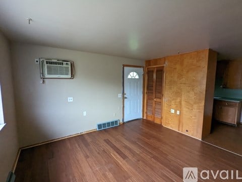 A room with wooden floors and a window on the left side.