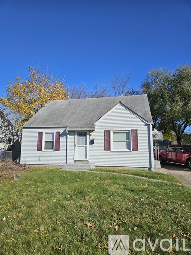 A small house with a red car parked in front.