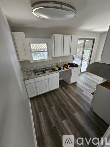 A kitchen with white cabinets and a wooden floor.