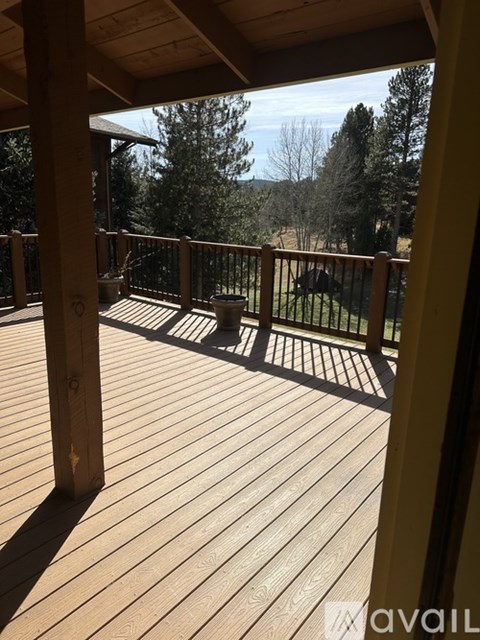 A wooden deck with a railing and a view of the trees.