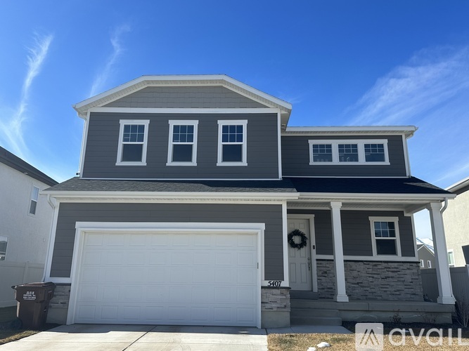 A two-story house with a white garage door and a grey roof.