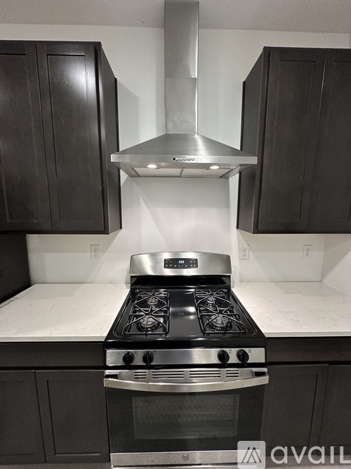 A modern kitchen with a stove top oven and dark wood cabinets.