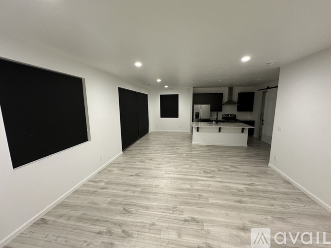 A spacious room with wooden flooring and white walls.