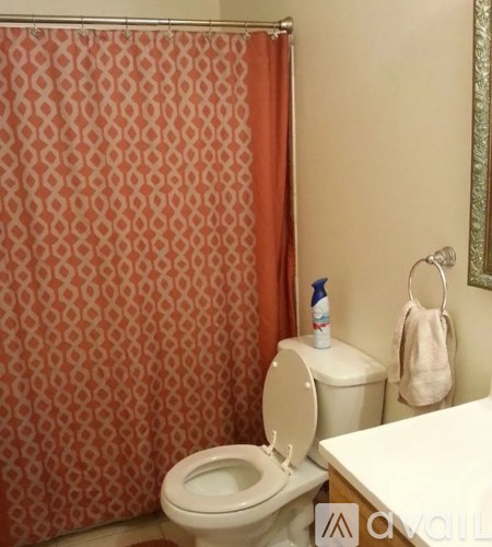 A toilet with a towel hanging on the wall behind it.