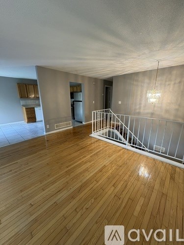 A spacious room with wooden flooring and a white railing.