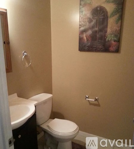 A bathroom with a toilet, sink and a painting on the wall.