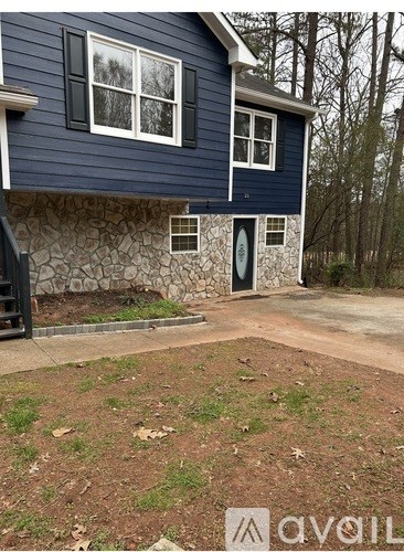 A blue house with a stone wall and a green lawn.