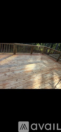 A wooden deck with a railing and a sunlit floor.