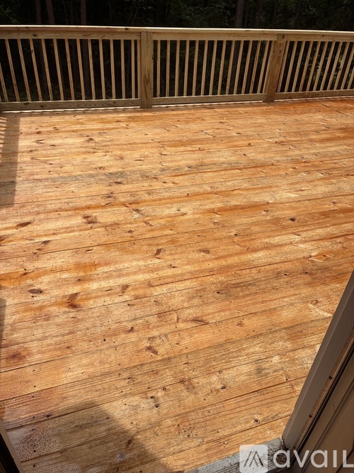 A wooden deck with a railing and a shadow of a tree.