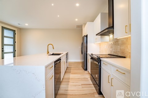 A modern kitchen with white cabinets and a marble countertop.