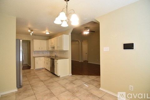 A kitchen with white cabinets and a fridge.