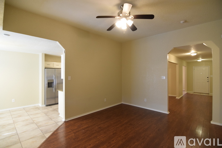 A spacious room with a ceiling fan and a refrigerator in the corner.