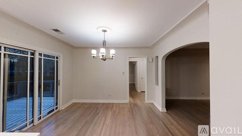 A spacious room with wooden flooring and a chandelier hanging from the ceiling.