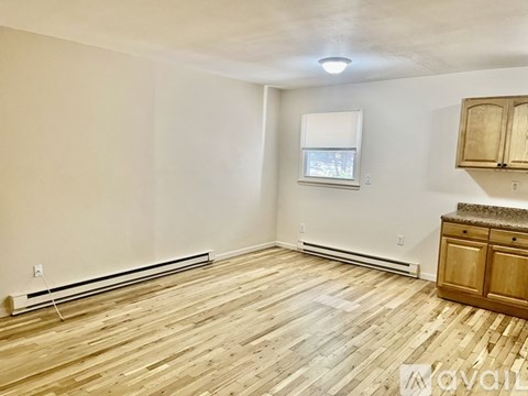 A room with wooden flooring and a window with blinds.