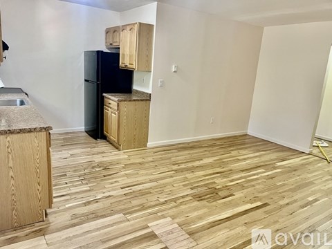 A kitchen with wooden floors and a black refrigerator.