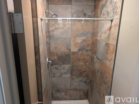 A shower with a glass door and a tiled wall.