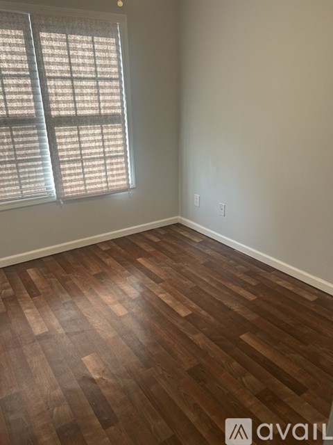 A room with wooden flooring and a window with blinds.