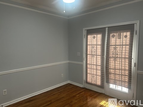 A room with a wooden floor and a sliding door with a window.