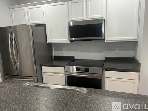 A kitchen with white cabinets and a stainless steel refrigerator.