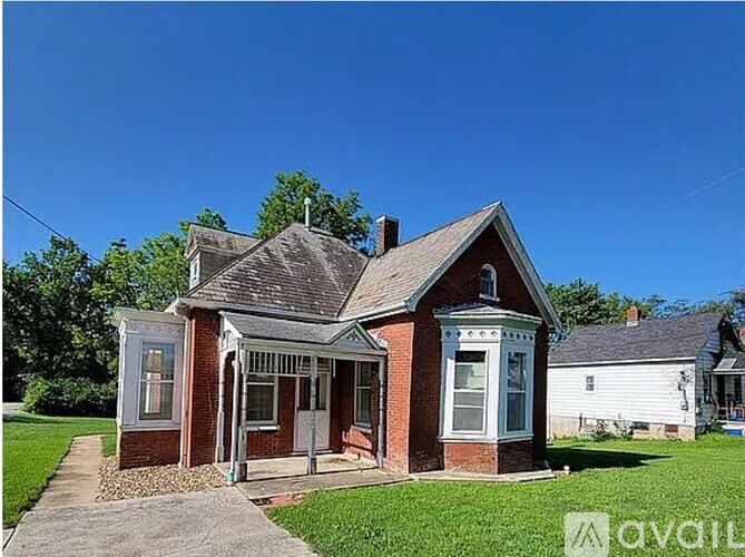 A small red brick house with a porch and a white door.