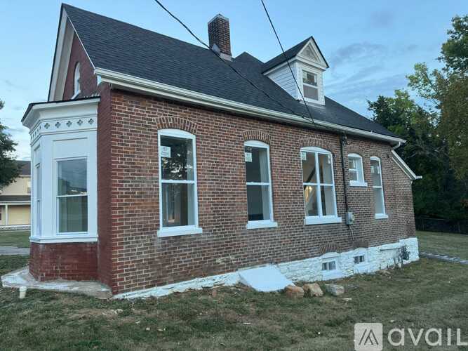 A brick house with a white window trim and a black roof.