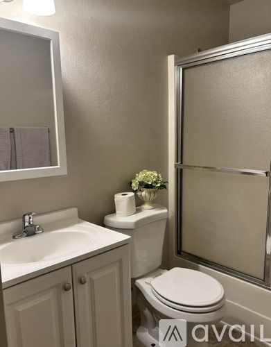 A bathroom with a toilet, sink, and mirror.