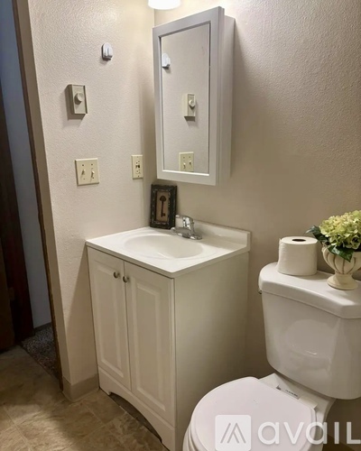 A white bathroom with a toilet, sink, and mirror.