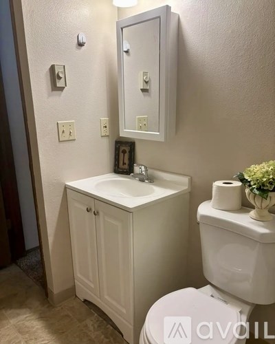 A white bathroom with a toilet, sink, and mirror.