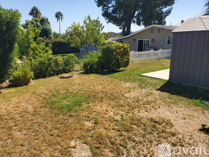 A backyard with a white fence and a house in the background.
