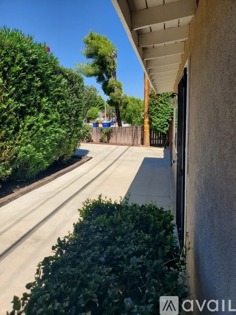 A residential street with a house on the right and a tree in the background.