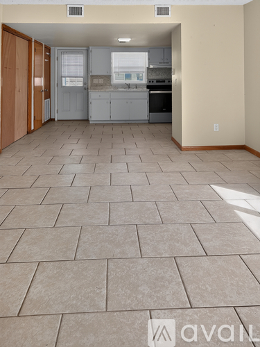 A kitchen area with tile flooring and a view into the dining area.