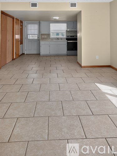 A kitchen area with tile flooring and a view into the dining area.
